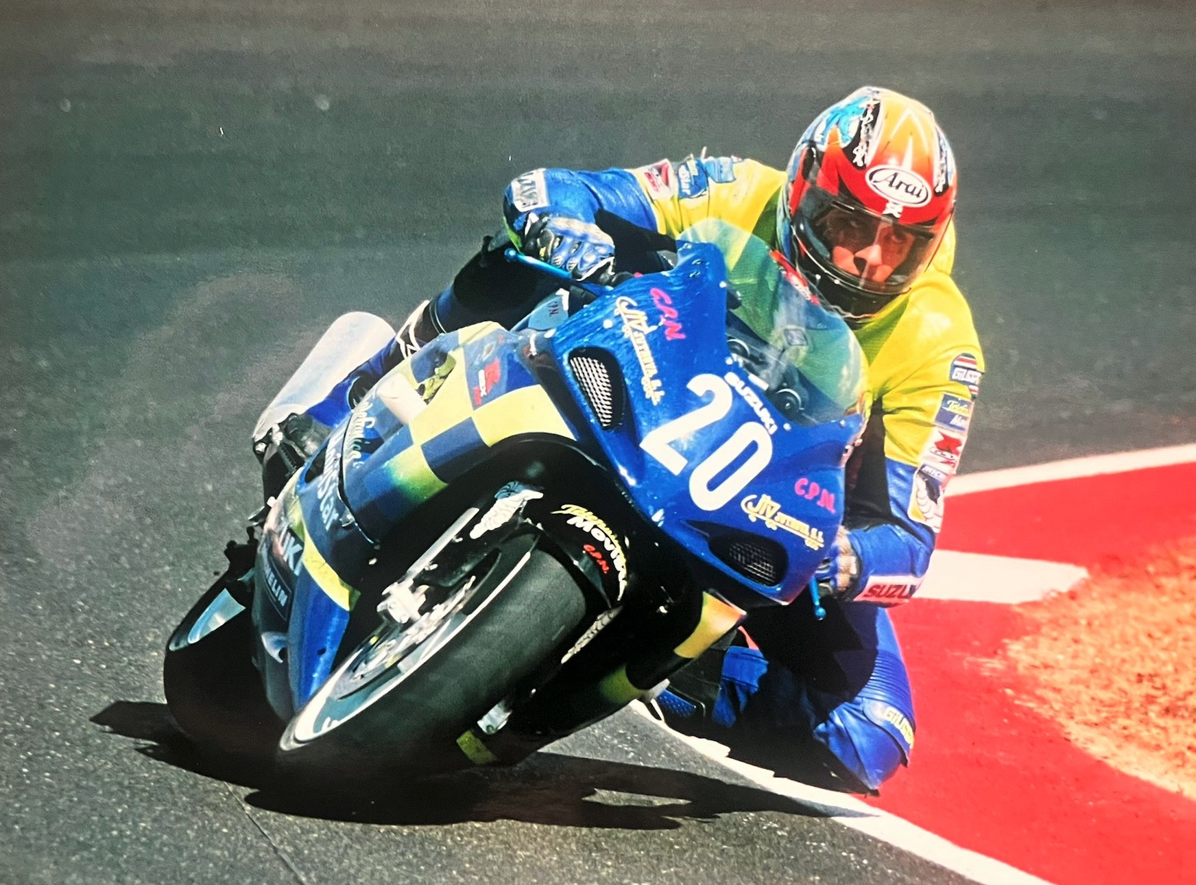 Jorge Díaz sobre Suzuki #20 azul inclinada en curva, mono amarillo y casco Arai