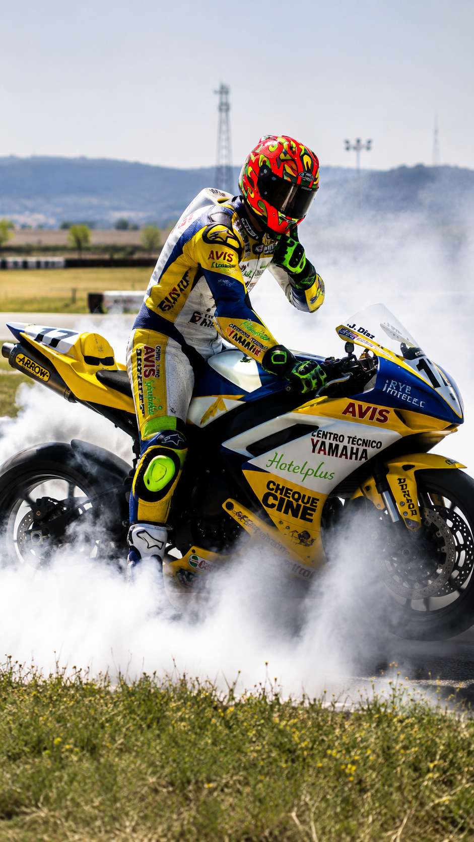 Jorge Díaz sobre Yamaha en burnout, casco rojo y amarillo con llamas, nube espesa de humo